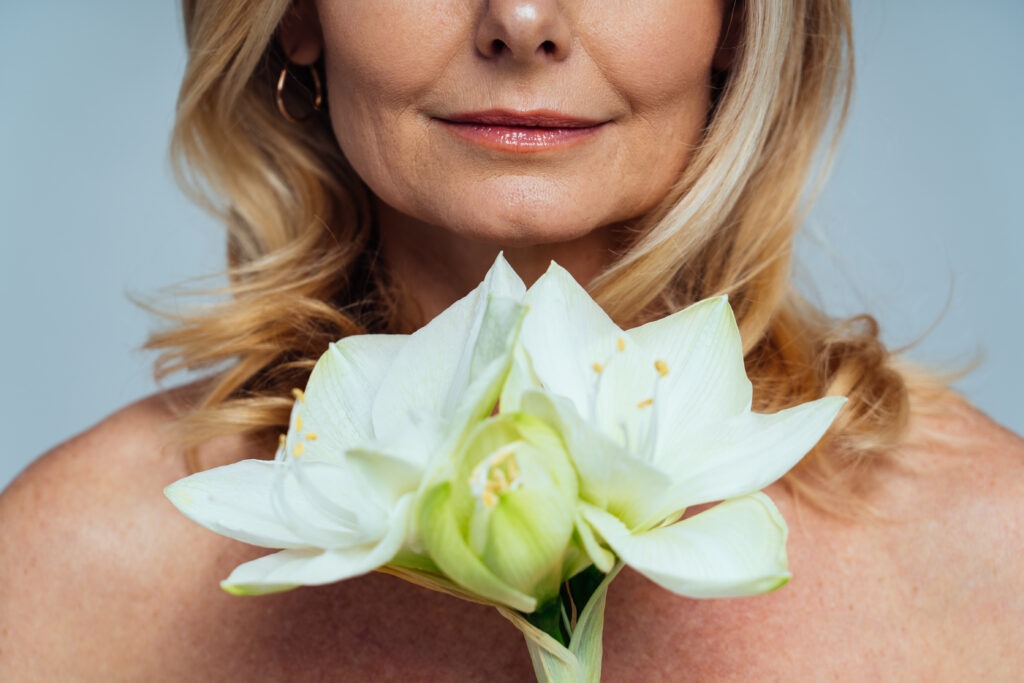 A woman with smooth, radiant skin holding a bouquet of fresh flowers, reflecting natural beauty and confidence after Botox treatment in Modesto.